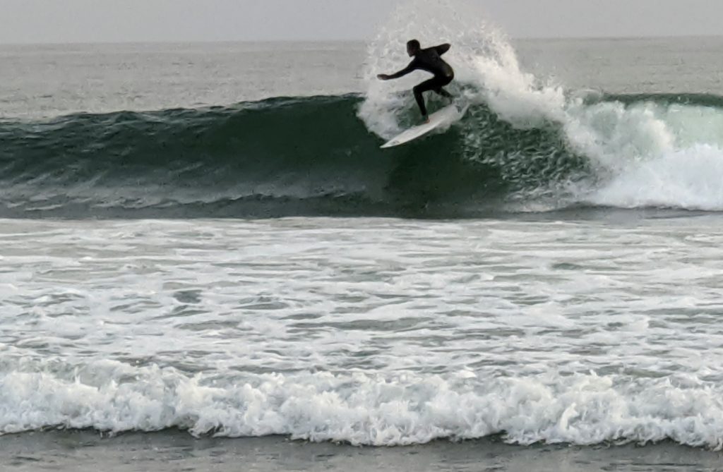 Surfer riding high on a wave at Topanga State Beach